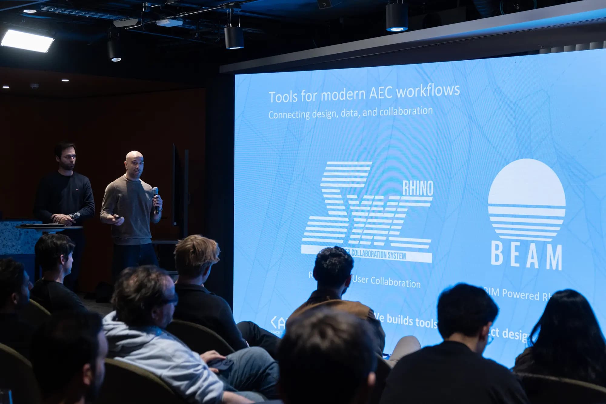 Mikael and Mauro presenting MKS DTECH tools on stage at an architecture industry event.